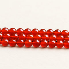 Crimson Reserve — Red Agate Round Beads on a warm ivory background