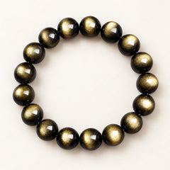 Golden Gaze — Gold Sheen Obsidian Bead Bracelet on a warm ivory studio background