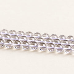 Crystal Reserve — Clear Quartz Round Beads on a warm ivory background