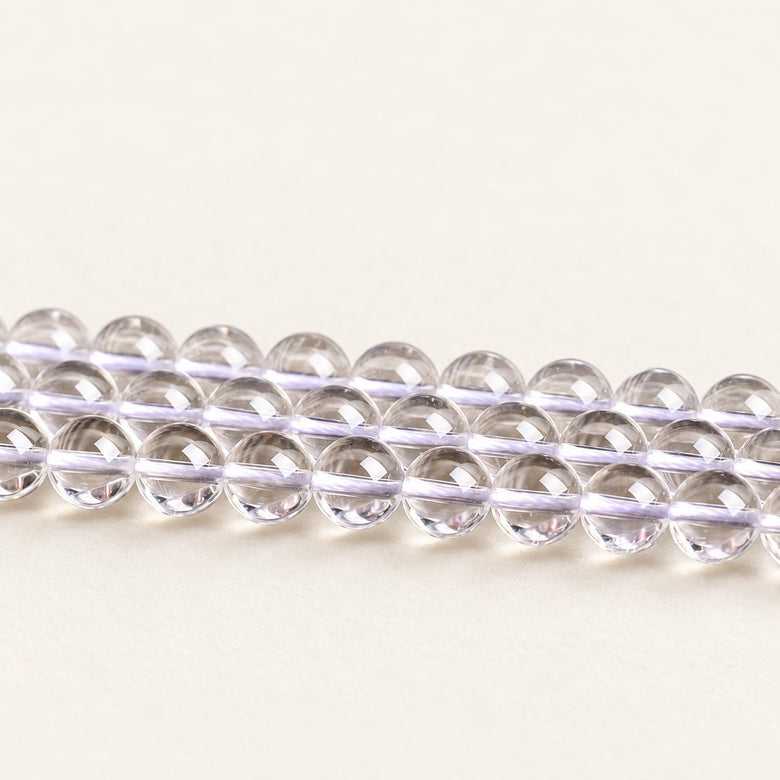 Crystal Reserve — Clear Quartz Round Beads on a warm ivory background