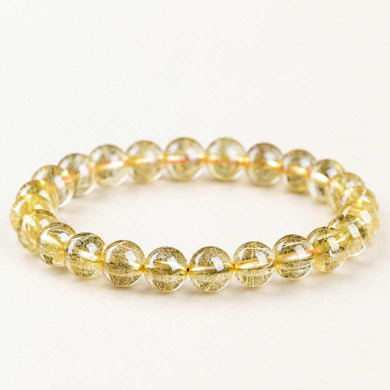 Golden Threads — Rutilated Quartz Bead Bracelet on a warm ivory background